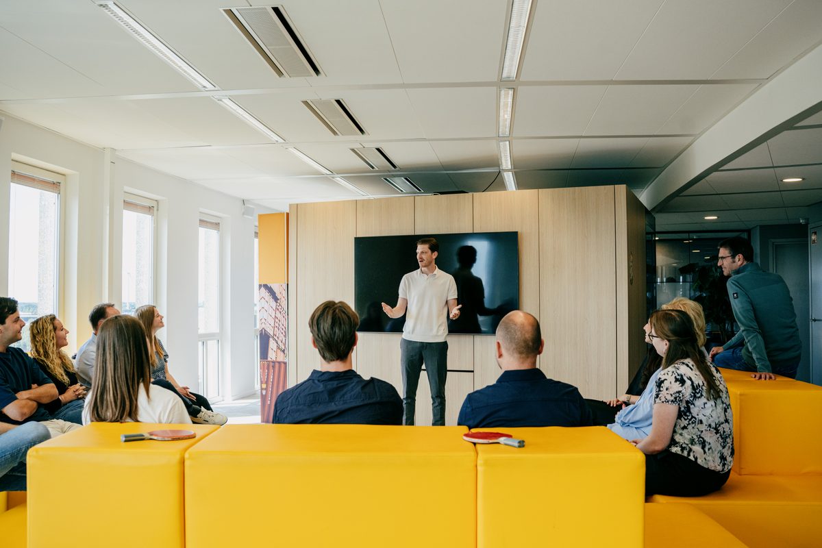 A trainer presenting to a group of seated trainees in a modern office